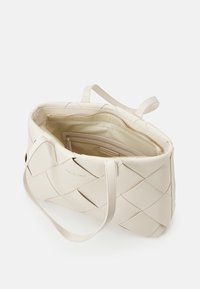 Beige vävd läder tote-väska med dubbla handtag, dragkedjeförsedd insida och logotypdetalj. Har en texturerad yta och ett rymligt huvudfack.