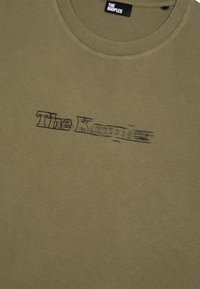 Camiseta de algodón color verde olivo con cuello redondo y el logo de "The Kooples" en negro, estilo difuminado, en el pecho.