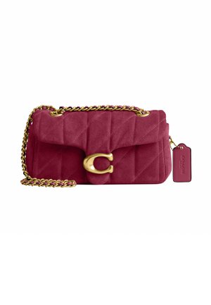 Petit sac à bandoulière en daim rose profond avec une bandoulière chaîne dorée, motif matelassé, grande boucle dorée et une étiquette rose suspendue sur le côté.