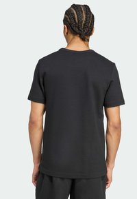 Μαύρο κοντομάνικο πουκάμισο με υφή, με κοφτή λαιμόκοψη. Η πλάτη έχει ελάχιστη ραφή και έχει άνετη εφαρμογή, σε συνδυασμό με αντίστοιχο σορτς.