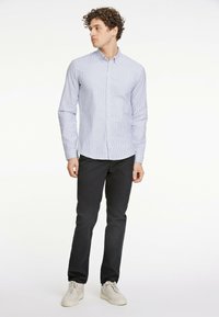 Koszula zapinana na guziki w jasnym niebieskim kolorze z białymi paskami, slim fit. Połączona z ciemnymi spodniami i jasnymi sneakerami. Gładki materiał, casualowy styl.