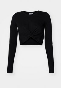 Zwarte geknipte langslijf t-shirt met lange mouwen, gemaakt van zacht materiaal, met een knoopdetail aan de voorkant en een ronde halslijn.