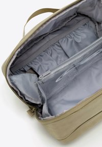 Beżowa torba materiałowa o gładkiej teksturze i zamknięciu na zamek błyskawiczny. Wewnątrz znajduje się szare wykończenie, kieszenie i kieszonki do organizacji.