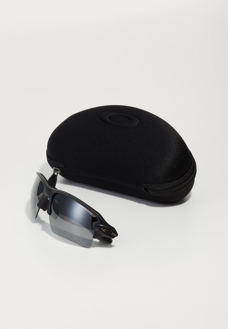 Black sports sunglasses with gray lenses, featuring a wraparound design and rubber accents, alongside a black protective case.
