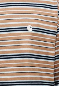 Κοντομάνικη ριγέ μπλούζα με εναλλασσόμενες λωρίδες σε καφέ, ναυτικό μπλε και ανοιχτό γαλάζιο. Μικρό λευκό λογότυπο τοποθετημένο στο στήθος.