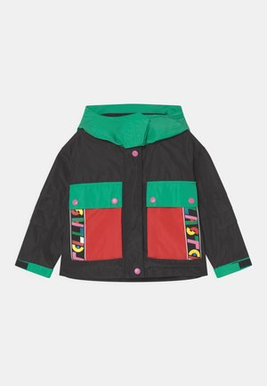 Chaqueta negra con capucha y puños verdes, bolsillos delanteros rojos con botones rosas y acentos de texto coloridos en los bordes de los bolsillos.