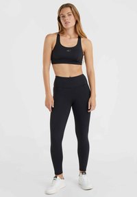 Mustat urheiluliivit ja korkeavyötäröiset leggingsit joustavasta, sileästä materiaalista. Liiveissä on hillitty logo; legginsit tarjoavat saumatonta muotoilua.