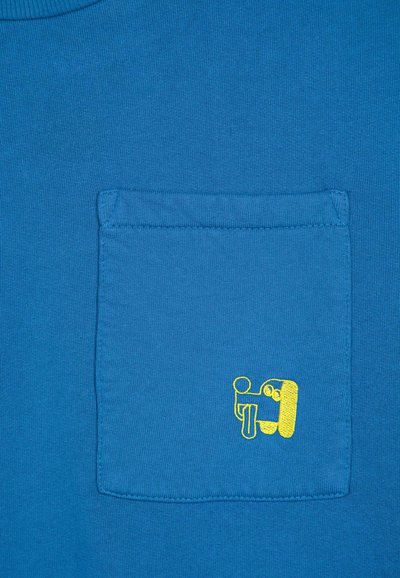 T-shirt in cotone blu con taschino a patch e grafica ricamata gialla, texture liscia e scollo a costine.