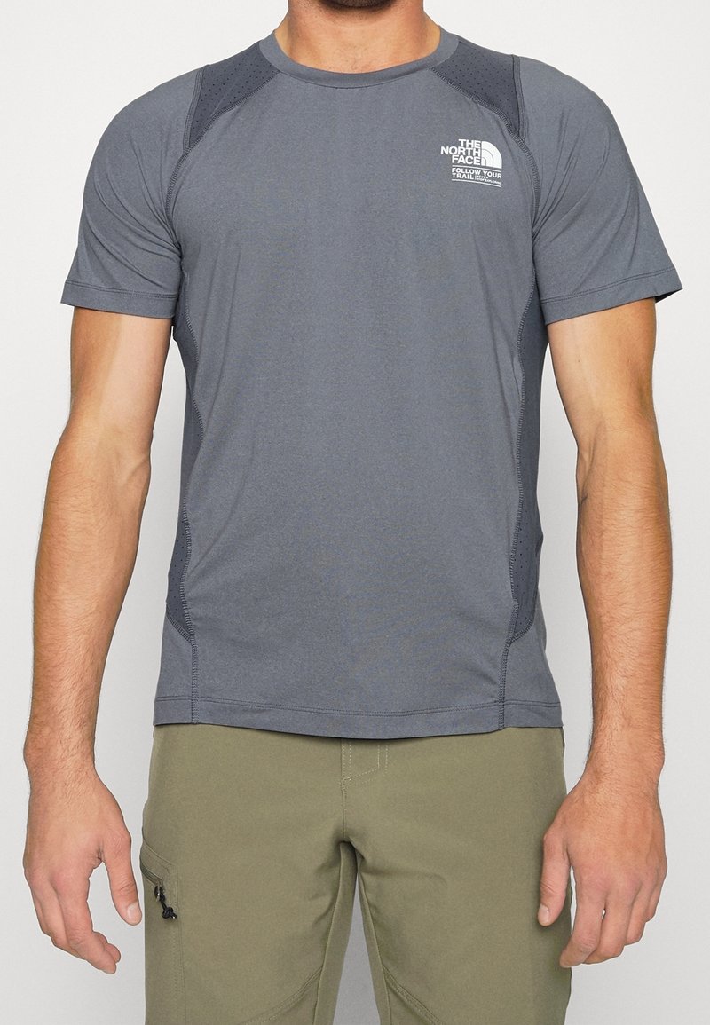 Šedé tričko s krátkým rukávem a raglánovými rukávy, s texturovanými detaily na ramenou a logem na hrudi. Hladká látka, přiléhavý design.