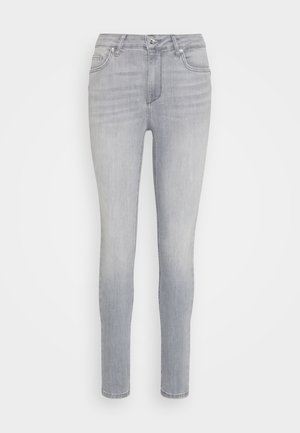 Jeans skinny gris clair avec cinq poches, une fermeture éclair et un seul bouton. Texture légèrement déchirée sur le tissu.