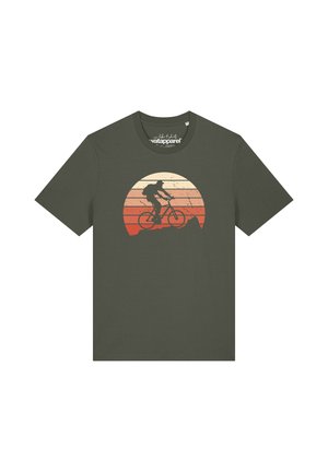 Olivgrünes T-Shirt mit einer Grafik eines Radfahrers, der bergauf fährt, vor einem runden Sonnenuntergangshintergrund in Beige- und Rottönen.
