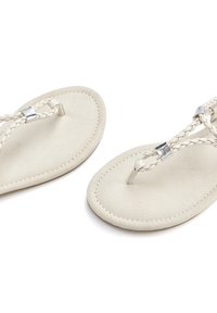 White leather flip-flops with braided straps and silver-tone hardware. Soft, flat sole with stitching around the edges.