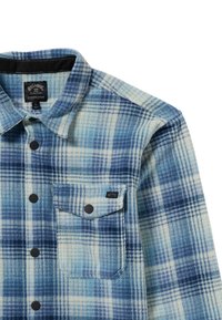 Camisa de franela a cuadros azules, con tonos que van del azul claro al azul oscuro, cuello abotonado, bolsillo en el pecho y botones negros. Textura suave con un patrón tejido.