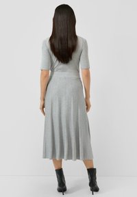 Szara, dopasowana sukienka z rozkloszowaną, midi spódnicą. Gładka, dzianinowa tekstura, krótkie rękawki typu "cap" oraz detal w postaci paska w talii. Noszona z czarnymi botkami za kostkę.