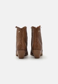 Botas de tobillo trenzadas de color marrón con un diseño texturizado y trenzado, que llegan a la mitad de la pantorrilla, con un borde ondulado y un pequeño tacón de madera.