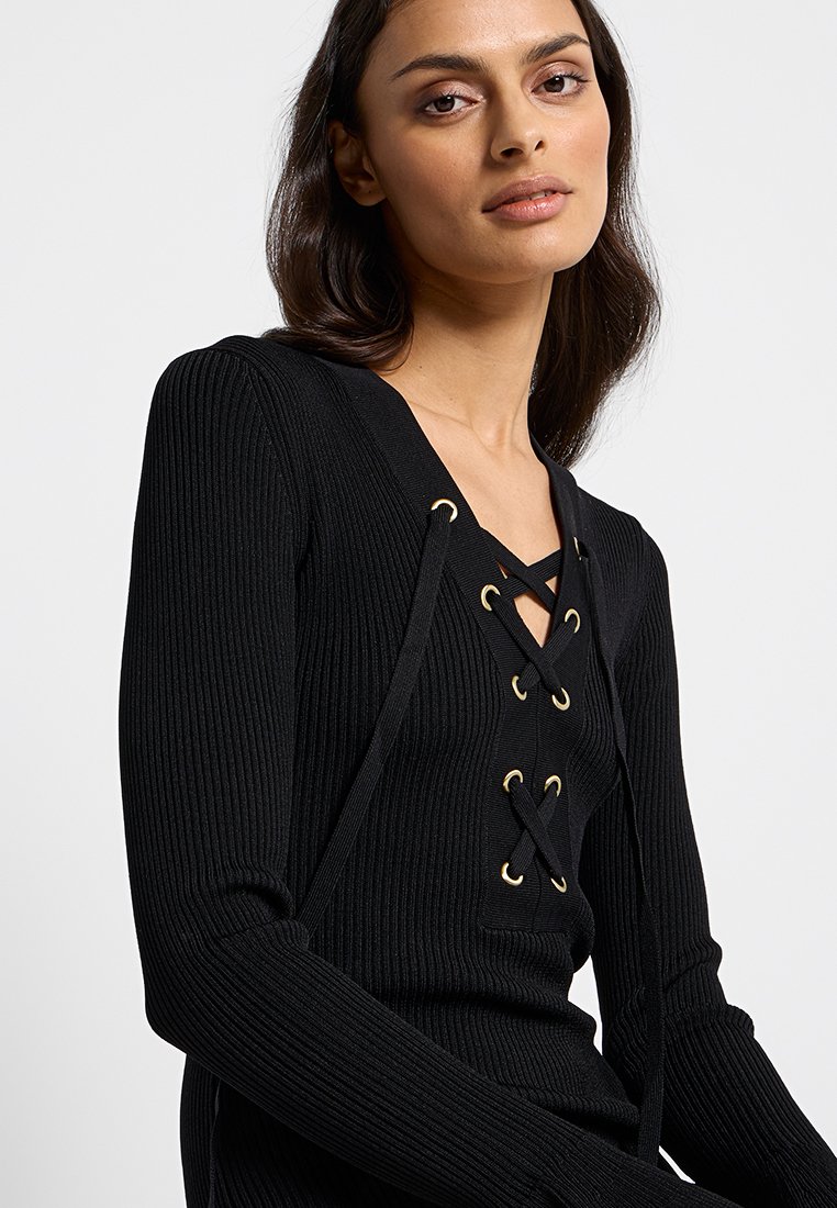 Czarna swetrowa bluzka z prążkowanym wzorem, z głębokim dekoltem w kształcie litery V, ozdobiona złotymi oczkami i sznurkami, z długimi rękawami oraz dopasowanym krojem.
