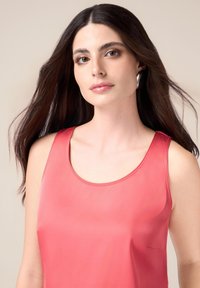 Koraalkleurig tanktop van een gladde, lichte stof met een ronde halslijn en zonder zichtbare versieringen of patronen. Eenvoudig ontwerp.