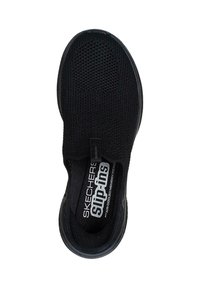 Zapato negro sin cordones con parte superior de malla texturizada, puntera redonda y plantilla acolchada etiquetada como "Espuma de Memoria Refrigerada por Aire". Suela plana de goma.
