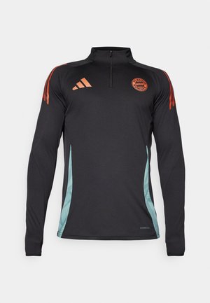 Camiseta atlética negra de manga larga con cremallera de un cuarto, acentos naranjas en los hombros y paneles laterales en color verde azulado con un patrón geométrico.