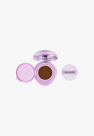 Boîtier compact violet avec fond de teint cushion marron et houppette blanche séparée étiquetée « Revolution ».