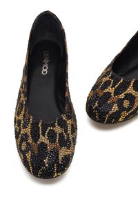 Een paar zwarte en gouden ballerina's met luipaardprint, bedekt met sprankelende rhinestones, op een witte achtergrond.