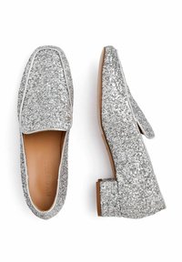 Stříbrné třpytivé loafers s kulatou špičkou a nízkým blokovým podpatkem. Obsahují prošívaný lem a hladkou koženou stélku. Plochá podrážka.