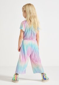 Färgglad, texturerad tvådelad outfit med pastellnyanser av rosa, blått och vitt; avslappnad passform med elastiskt midjeband; kombinerad med iridenscenta sneakers.