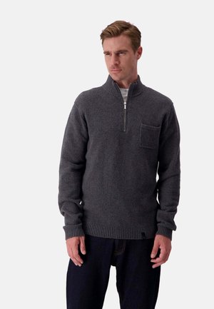 Grauer Strickpullover mit hohem Kragen, kurzem Reißverschluss vorne und einer Brusttasche. Gerippte Bündchen und Saum verleihen der Textur zusätzliche Effekte.
