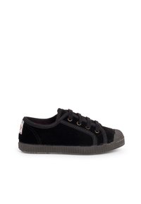 Sneaker nero a bassa altezza con lacci neri, punta in gomma, suola testurizzata e una piccola etichetta bianca sul tallone.