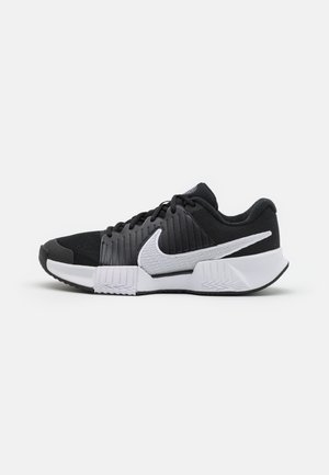 Mustvalged ja valged spordijalatsid tekstuuriga ülemise osaga, tugevdustega konts ja silmapaistev swoosh logo. Lame põhi mustriga haardumise jaoks.