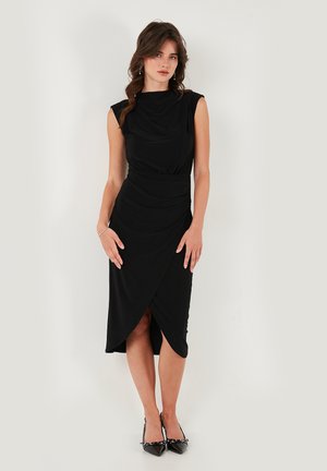 Schwarzes Kleid mit drapiertem, ärmellosem Design, tailliertem Bund und asymmetrischem Wickelrock. Glattes, seidiges Material mit subtiler Eleganz.