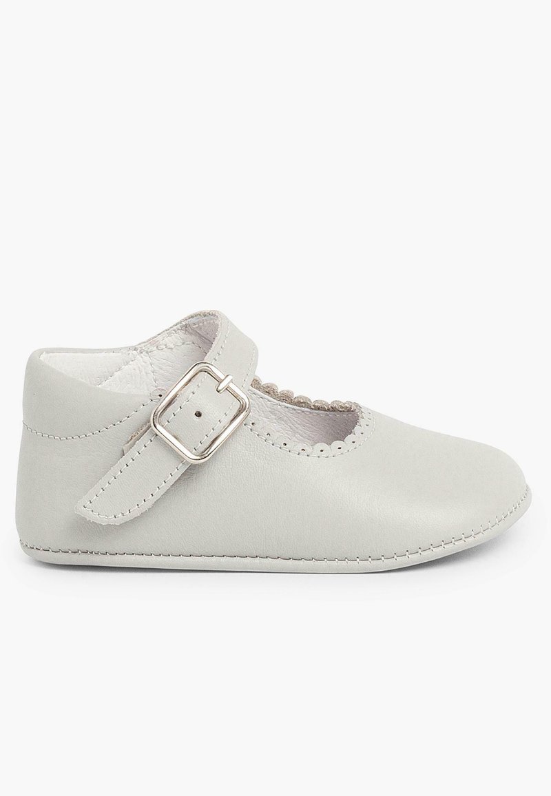 Zapato de bebé de cuero gris claro con punta redonda, borde festoneado y correa ajustable con hebilla. Textura suave y detalles de costura.
