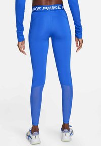 Leggings deportivos azules con una cinta alta en la cintura que presenta el logotipo en blanco de "NIKE". Fabricados con una tela elástica y paneles de malla en la parte inferior de las piernas.