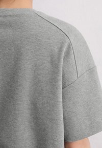 Gray short-sleeve t-shirt made of soft cotton, featuring a round neckline and set-in sleeves with visible stitching along the seams.