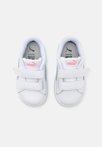 Baskets blanches avec une tige en cuir lisse, des accents teal et un logo rose. Comprend un col rembourré et deux bandes velcro pour la fermeture.