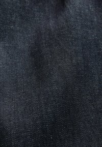 Primer plano de tela vaquera azul oscuro que muestra una textura detallada y un patrón de tejido con sutiles reflejos de luz.