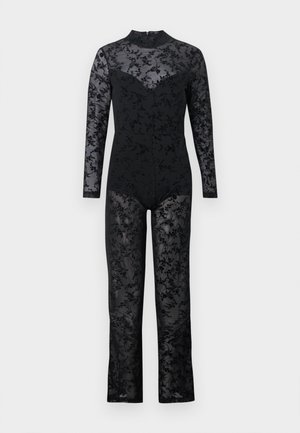 Monos de color negro con mangas largas, que presentan un patrón de encaje floral texturizado y transparente, además de un cuello alto. Cuerpo ajustado con piernas acampanadas.