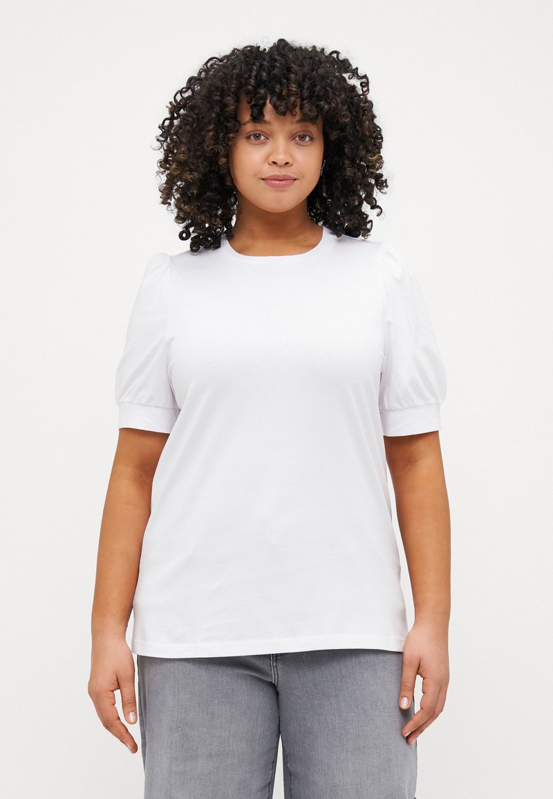 White short-sleeve top with puffed sleeves, round neckline, and smooth cotton texture. Paired with light gray jeans.