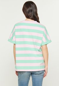 Kortærmet, afslappet t-shirt i alternierende pastelfarvet pink og grønne horisontale striber. Blødt stof med rund halsudskæring og opkrøllede ærmer.