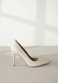 Beige patent leather korkokengät, joissa on kapea kärki, tyylikäs muotoilu ja ohut stiletto-korko. Sujuva pinta, jossa on kiiltävä viimeistely.