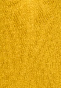 Gult strikket stoff med middels tekstur, som har et fint, jevnt maskemønster og en varm, lys nyanse.