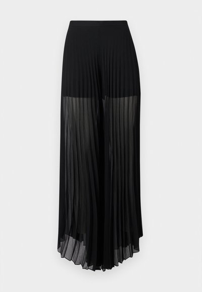 Μαύροι ψηλόμεσοι φαρδιά μπατζάκια με πιέτες και διαφανές ύφασμα από το μέσο του μηρού έως το τελείωμα, παρουσιασμένοι σε απλό φόντο.