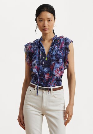 Floral print top in shades of blue, purple, and pink. Features ruffled short sleeves and a drawstring neckline. Paired with white jeans.