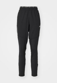 Czarne sportowe spodnie o zwężanym kroju, z elastycznym pasem i białymi paskami po bokach. Wykonane z lekkiego, oddychającego materiału.