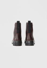 Mørkebrune lærankleboots med en glat overflade, sorte detaljer, elastiske sidepaneler og en solid sort gummisål.