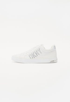 Weiße Sneaker mit einem Obermaterial aus glattem Leder, flacher Sohle, Schnürung und einem funkelnden "DKNY"-Logo-Akzent an der Seite.