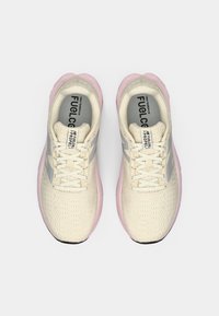 Krem- og rosa New Balance FuelCell Propel løpesko med snøring, sett ovenfra på en hvit bakgrunn.