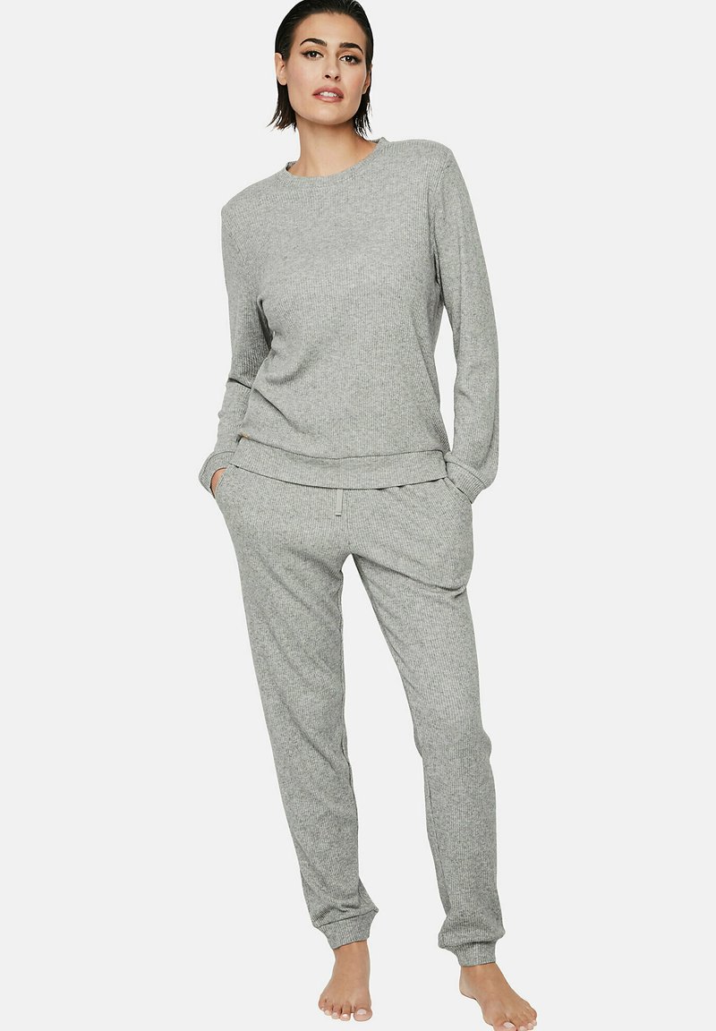 Ensemble de loungewear en gris côtelé comprenant un haut à col rond à manches longues et un pantalon de jogging à cordon avec des chevilles resserrées. Texture douce et coupe décontractée.