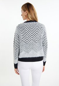 Flauschiger Pullover mit Chevron-Muster in Schwarz und Weiß, mit geripptem schwarzen Saum und Bündchen. Kurze, lässige Passform.