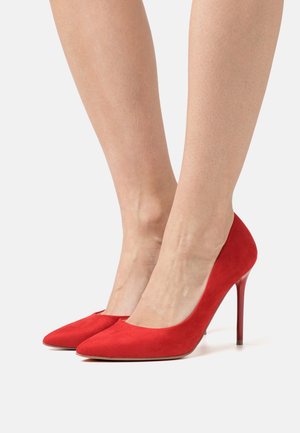Rote Wildleder-High Heels mit spitzem Zehenbereich und dünnem Stiletto-Absatz. Glatte Textur mit einem einfachen, eleganten Design.